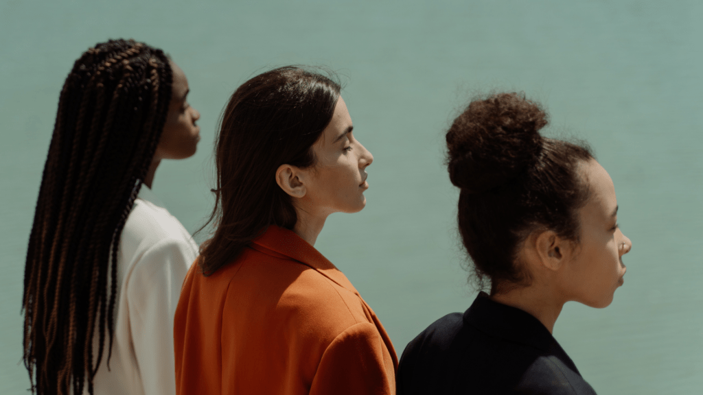 What's the impact of fast fashion on the environment? Ocean Generation is diving into fast fashion, textile production, where clothing actually goes when we recycle it and how we can all be sustainable fashion lovers. Image is of three ethnically diverse and fashionable women, looking off into the distance. They're each wearing a power suit.