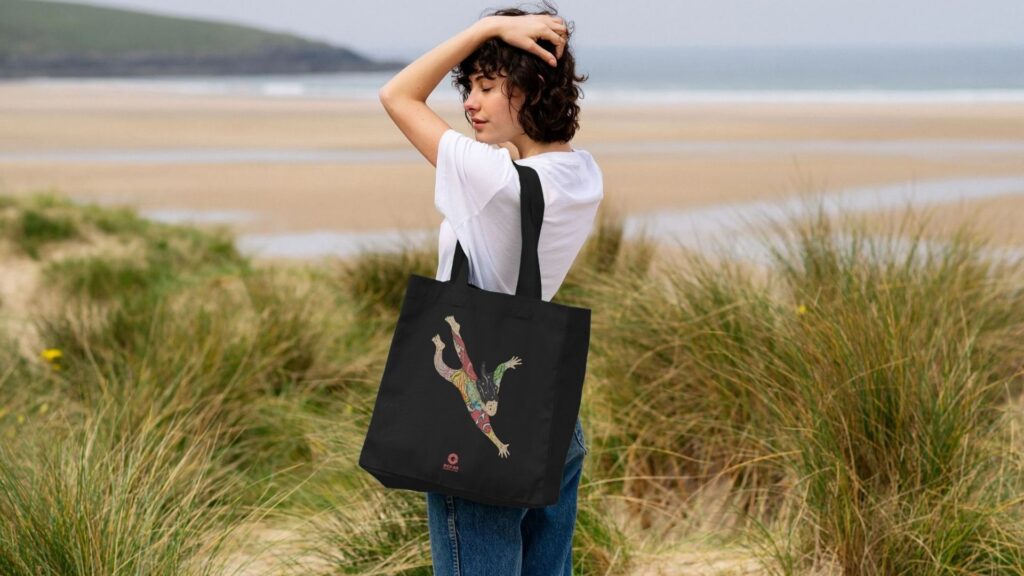 Woman on the beach, with an Ocean-friendly beach bag sold by Ocean Generation. Beach bag perfect for Ocean lovers. Ocean Generation's clothing products are all sustainable, using organic cotton and 100% renewable energy to manufacture the items.